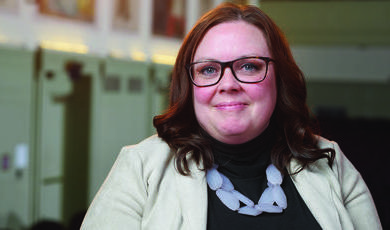 A woman wearing glasses smiles at the camera 